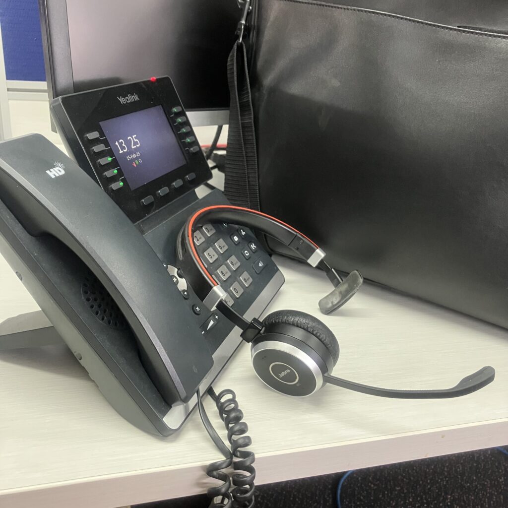 a desk phone with headset resting against it