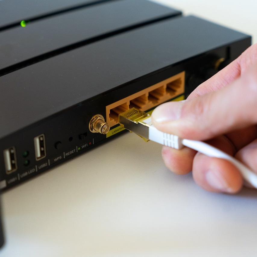 close-up of a man plugging an ethernet cable into a router