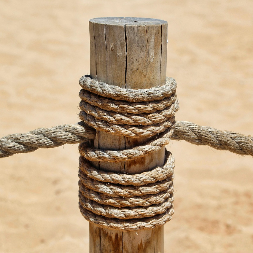 ropes tied onto a wooden post on earth or beach